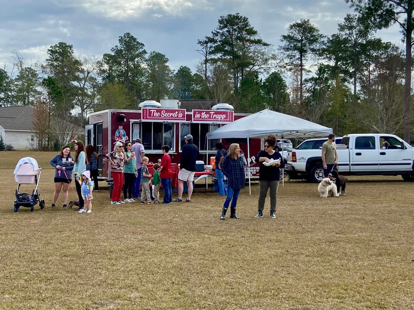 The Rollin' Trapp trailer and canopy serving a crowd of families at a community event.
