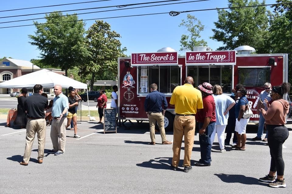 Office workers queuing at The Rollin' Trapp trailer for a corporate lunch in a car park.