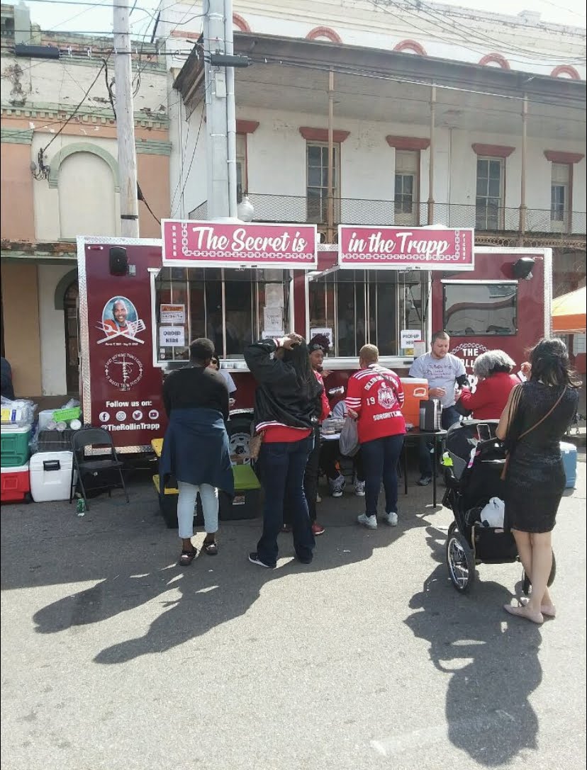 The Rollin' Trapp trailer set up on a downtown street with a queue of customers during a festival.